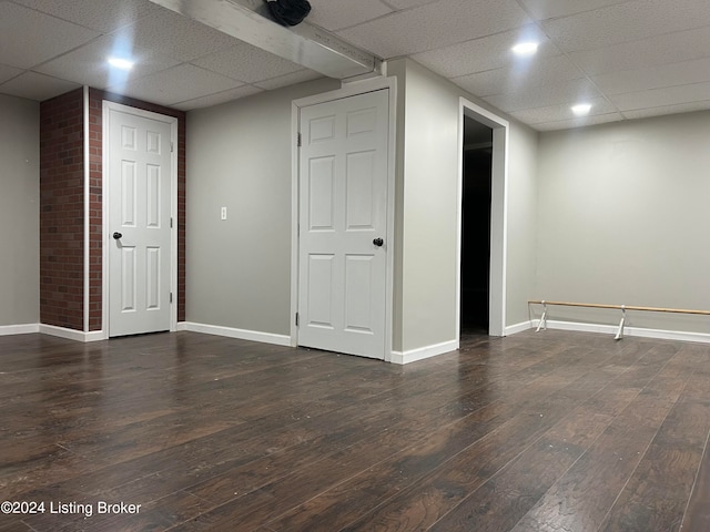 basement with a drop ceiling and dark wood-type flooring