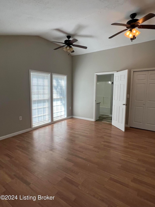 unfurnished bedroom featuring ceiling fan, vaulted ceiling, a textured ceiling, and dark hardwood / wood-style flooring