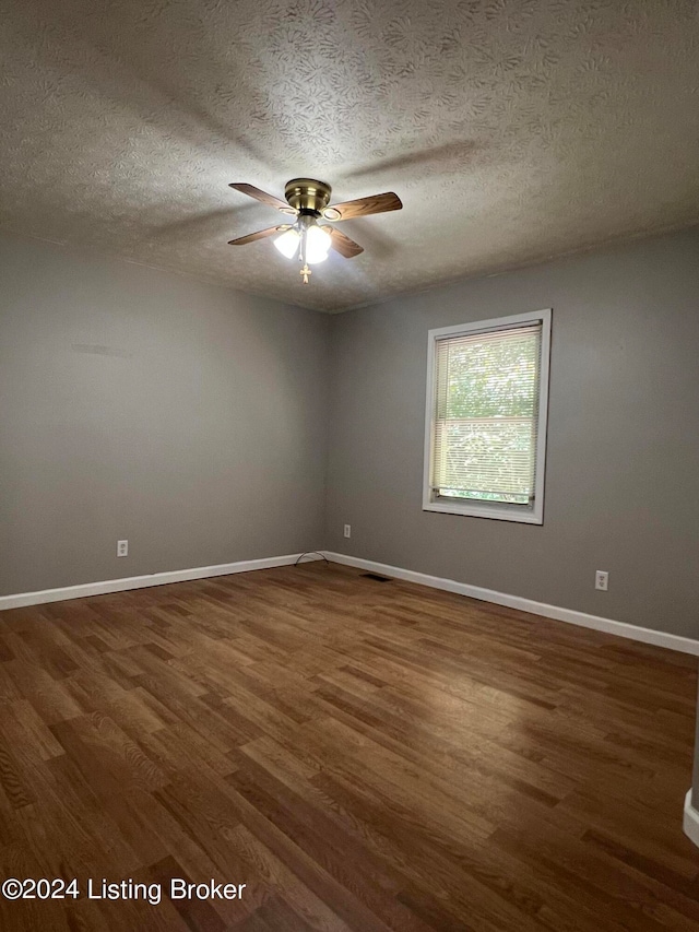 unfurnished room with ceiling fan, dark wood-type flooring, and a textured ceiling