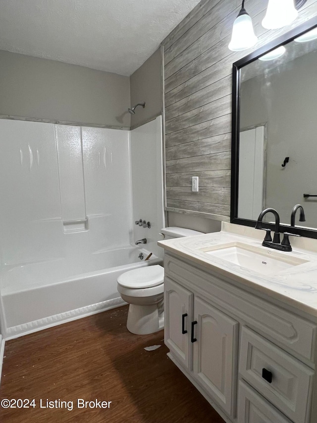 full bathroom with bathing tub / shower combination, vanity, a textured ceiling, hardwood / wood-style floors, and toilet