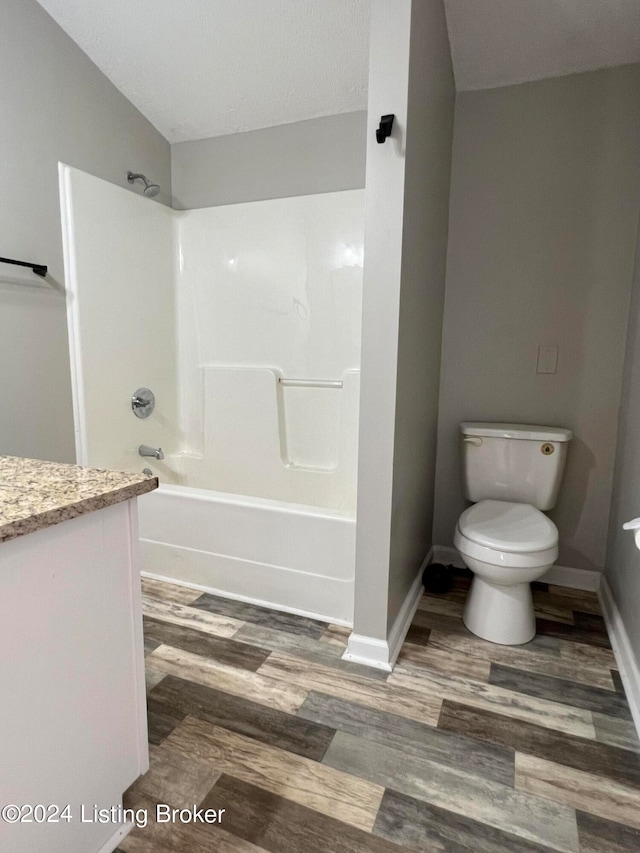 full bathroom with lofted ceiling, hardwood / wood-style floors, shower / bathing tub combination, vanity, and toilet