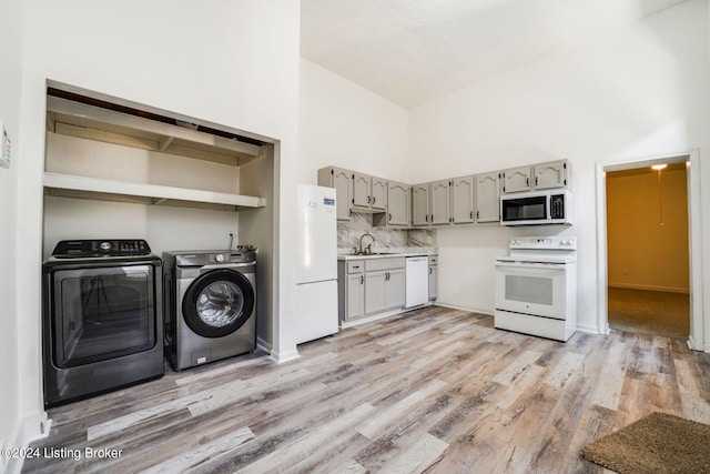 interior space featuring light wood-type flooring, a towering ceiling, washer and clothes dryer, and sink