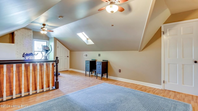 additional living space featuring light hardwood / wood-style flooring, ceiling fan, and lofted ceiling with skylight