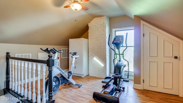 exercise room featuring ceiling fan, light wood-type flooring, and vaulted ceiling