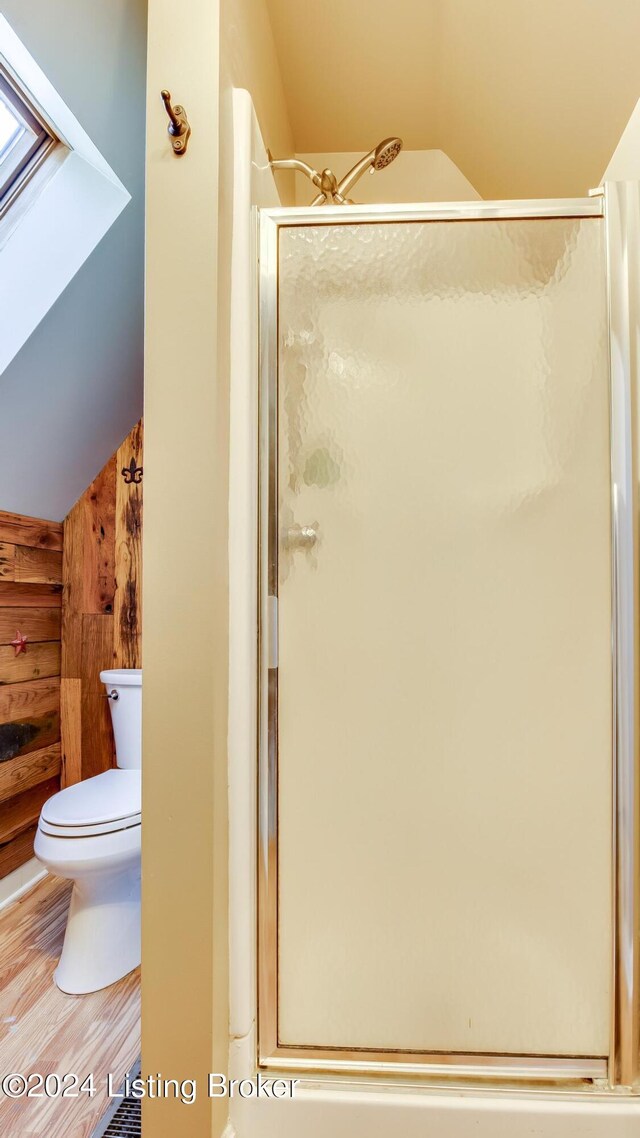 bathroom with wooden walls, vaulted ceiling, an enclosed shower, and toilet