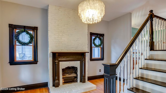 entryway featuring a notable chandelier, a brick fireplace, and light hardwood / wood-style floors