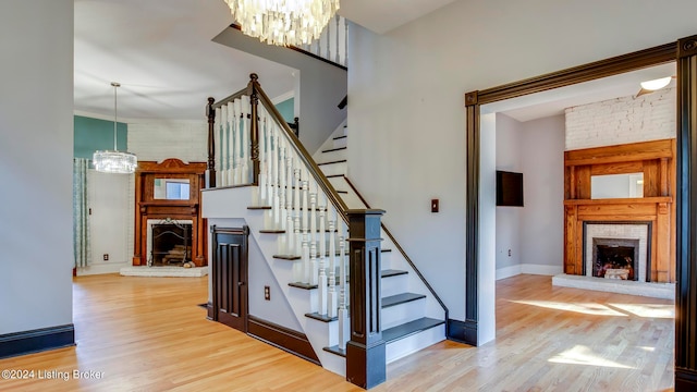 staircase with hardwood / wood-style flooring, a fireplace, and a chandelier