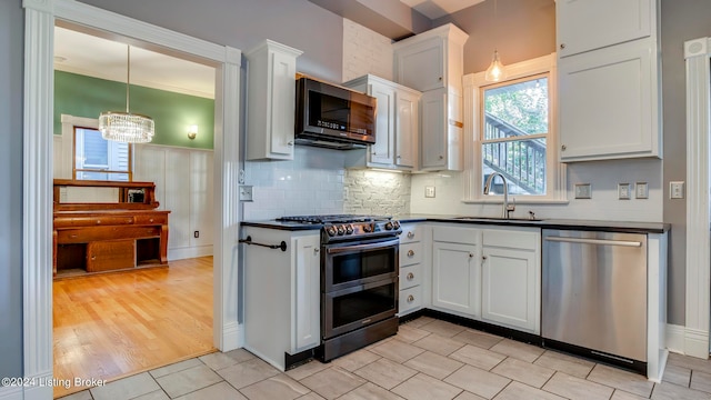 kitchen with light wood-type flooring, a chandelier, sink, white cabinets, and appliances with stainless steel finishes