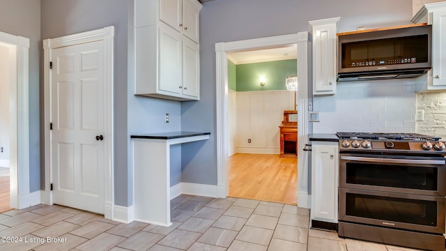 kitchen with light hardwood / wood-style floors, tasteful backsplash, white cabinetry, stainless steel appliances, and crown molding