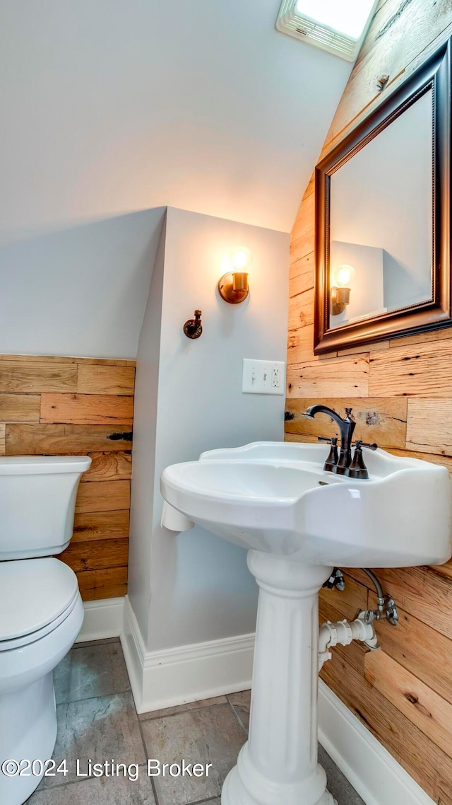 bathroom with toilet, wood walls, and vaulted ceiling