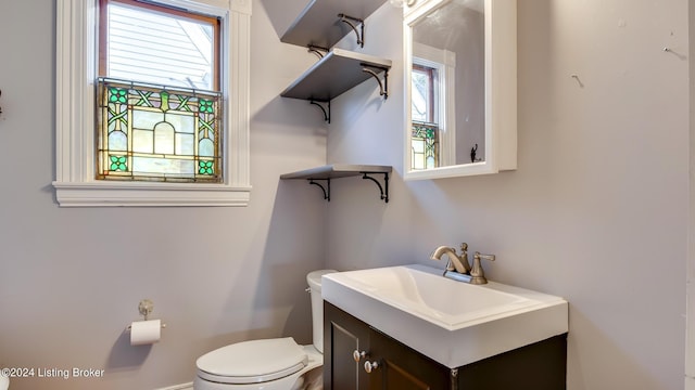 bathroom with vanity, toilet, and a healthy amount of sunlight