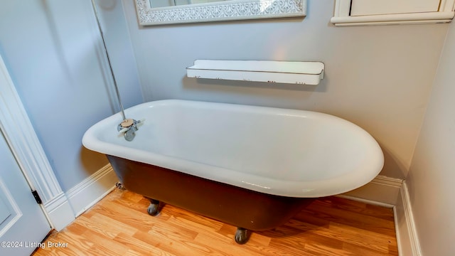 bathroom with a tub to relax in and hardwood / wood-style flooring