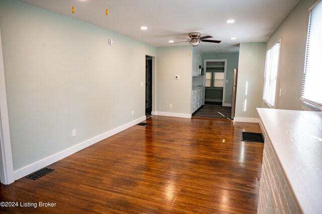 unfurnished living room featuring ceiling fan and dark wood-type flooring