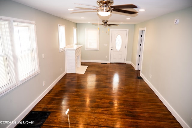 foyer featuring ceiling fan, dark hardwood / wood-style flooring, and a brick fireplace