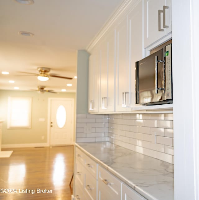 kitchen featuring ceiling fan, white cabinetry, backsplash, and light hardwood / wood-style flooring