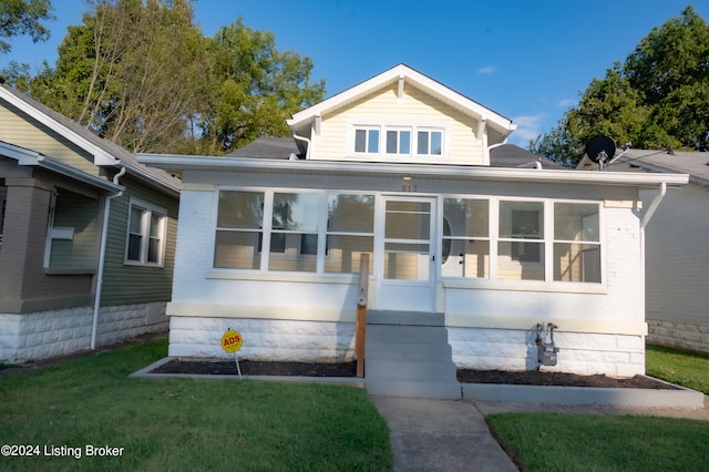 bungalow-style house featuring a sunroom and a front lawn