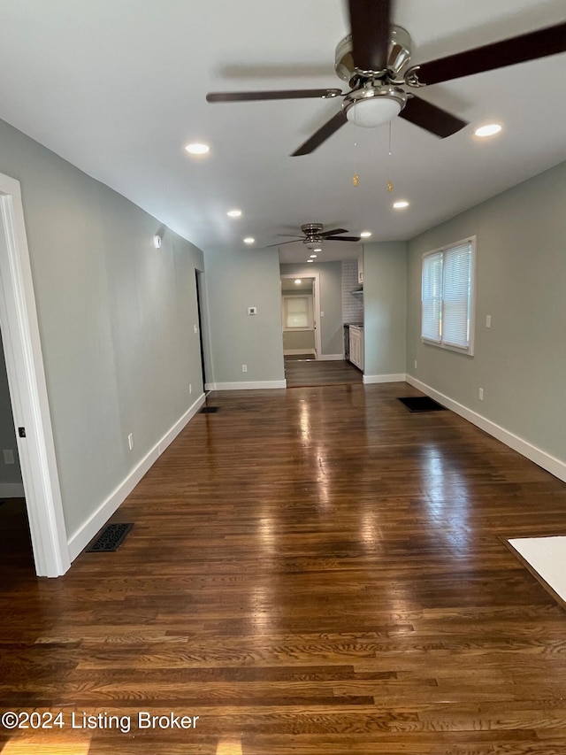 unfurnished living room featuring ceiling fan and dark hardwood / wood-style flooring