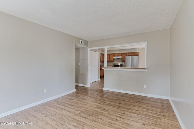 unfurnished living room with light hardwood / wood-style flooring and a textured ceiling