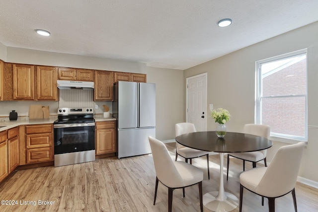 kitchen featuring appliances with stainless steel finishes, a textured ceiling, and light hardwood / wood-style floors