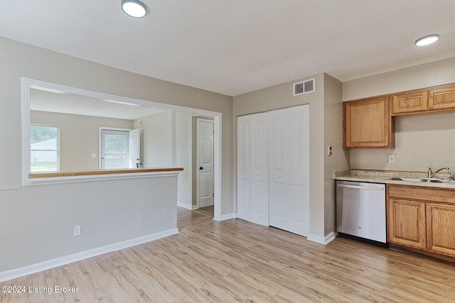 kitchen with light wood-type flooring, a textured ceiling, stainless steel dishwasher, and sink