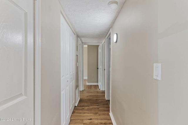 corridor featuring a textured ceiling and hardwood / wood-style floors