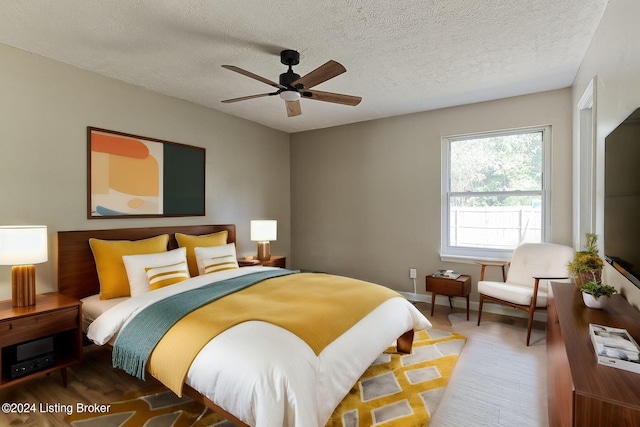 bedroom with ceiling fan, dark hardwood / wood-style floors, and a textured ceiling