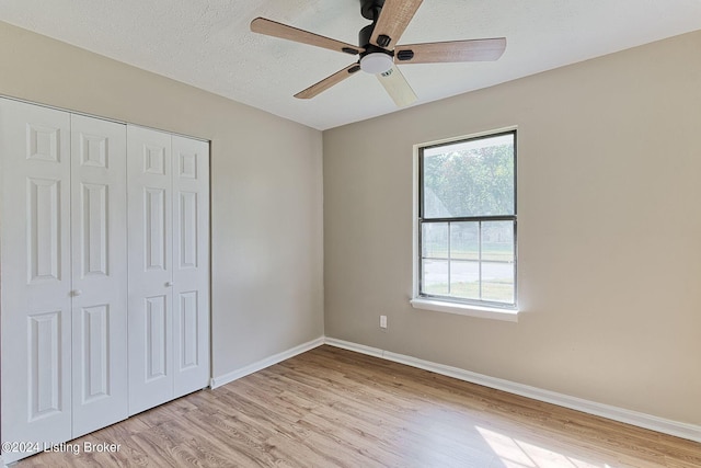 unfurnished bedroom featuring ceiling fan, a textured ceiling, light hardwood / wood-style flooring, and a closet