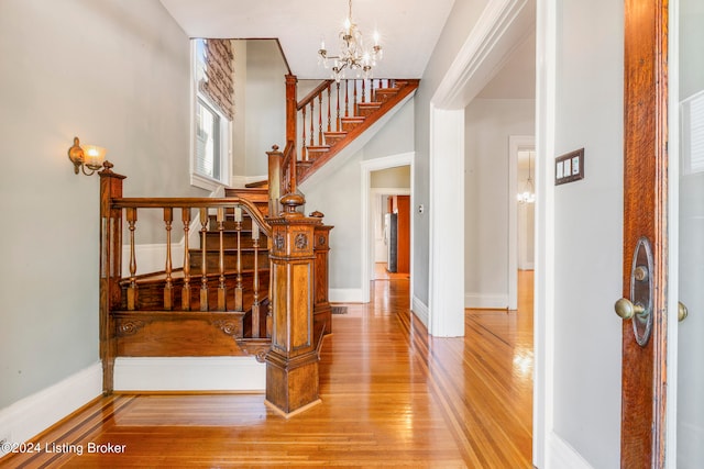 stairs with a notable chandelier and hardwood / wood-style floors