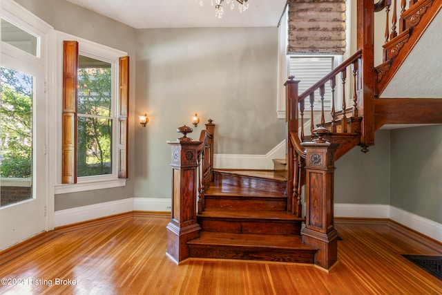 staircase with wood-type flooring and a chandelier