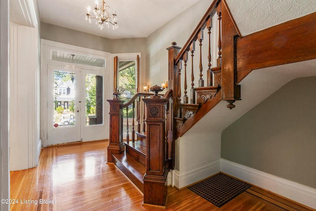 entrance foyer featuring an inviting chandelier, french doors, and light hardwood / wood-style floors