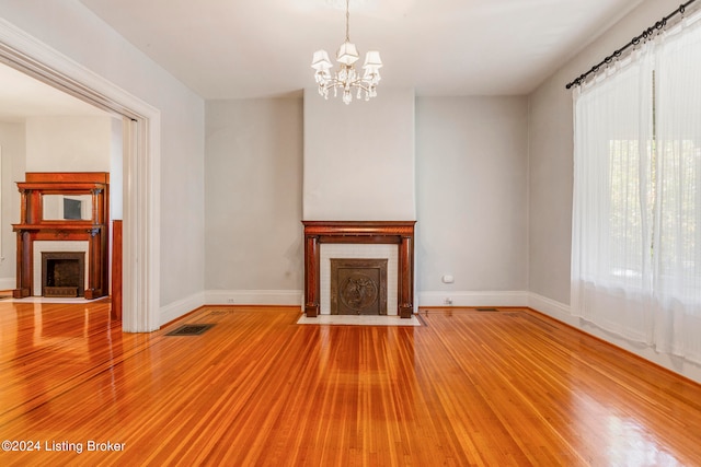 unfurnished living room featuring an inviting chandelier and hardwood / wood-style flooring