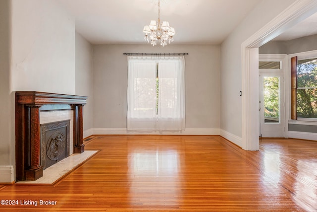 unfurnished living room featuring a chandelier and light hardwood / wood-style floors