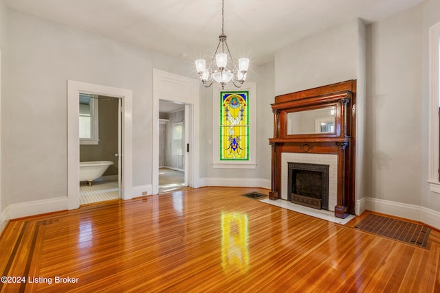 unfurnished living room with a fireplace, hardwood / wood-style floors, and an inviting chandelier