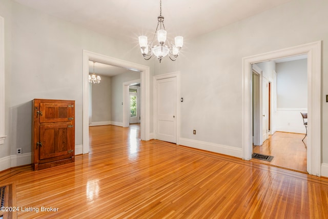 unfurnished room featuring light wood-type flooring and a chandelier