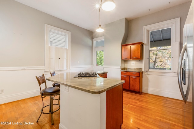 kitchen featuring hanging light fixtures, light hardwood / wood-style floors, and a healthy amount of sunlight