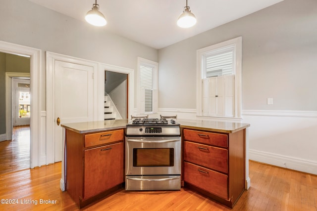 kitchen featuring decorative light fixtures, light hardwood / wood-style floors, and stainless steel gas stove