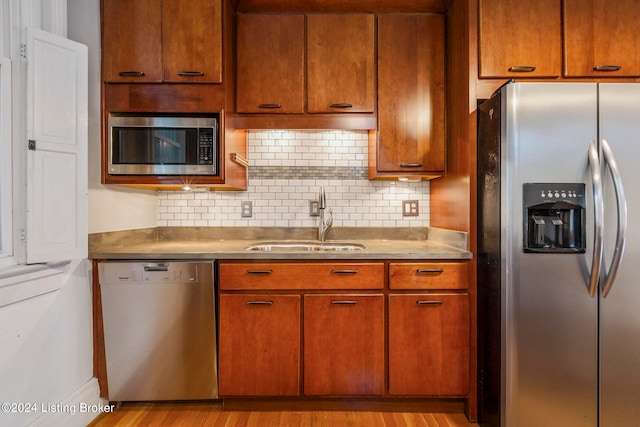 kitchen with light hardwood / wood-style floors, sink, stainless steel appliances, and backsplash