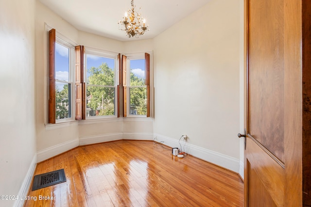 spare room featuring hardwood / wood-style flooring and an inviting chandelier