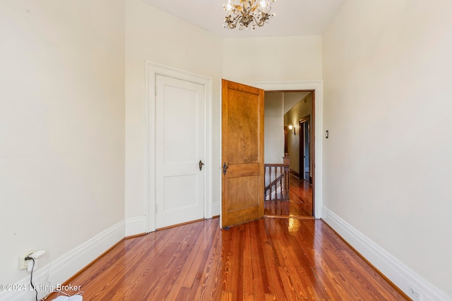 unfurnished room with wood-type flooring and a chandelier