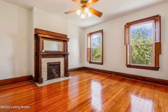 unfurnished living room featuring ceiling fan, a fireplace, and light hardwood / wood-style floors