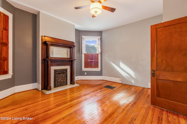 unfurnished living room featuring a brick fireplace, light hardwood / wood-style flooring, and ceiling fan