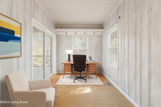 home office featuring ornamental molding, wooden walls, and light wood-type flooring