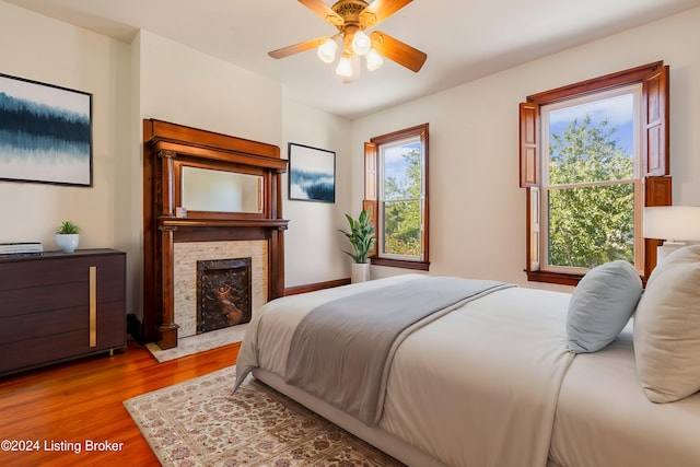 bedroom with hardwood / wood-style flooring, a fireplace, and ceiling fan