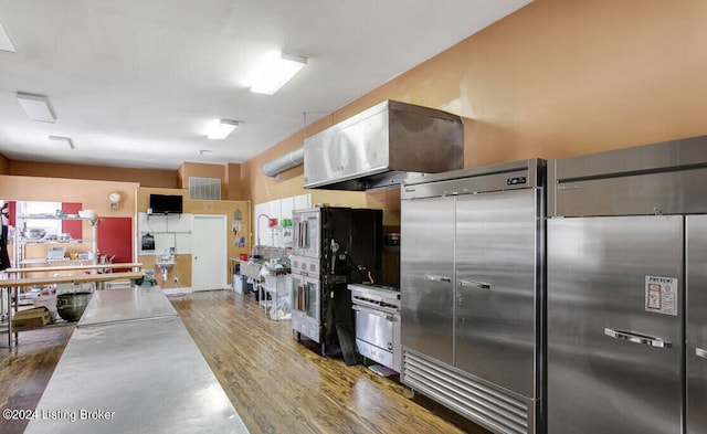 kitchen featuring range hood, a healthy amount of sunlight, appliances with stainless steel finishes, and dark wood-type flooring