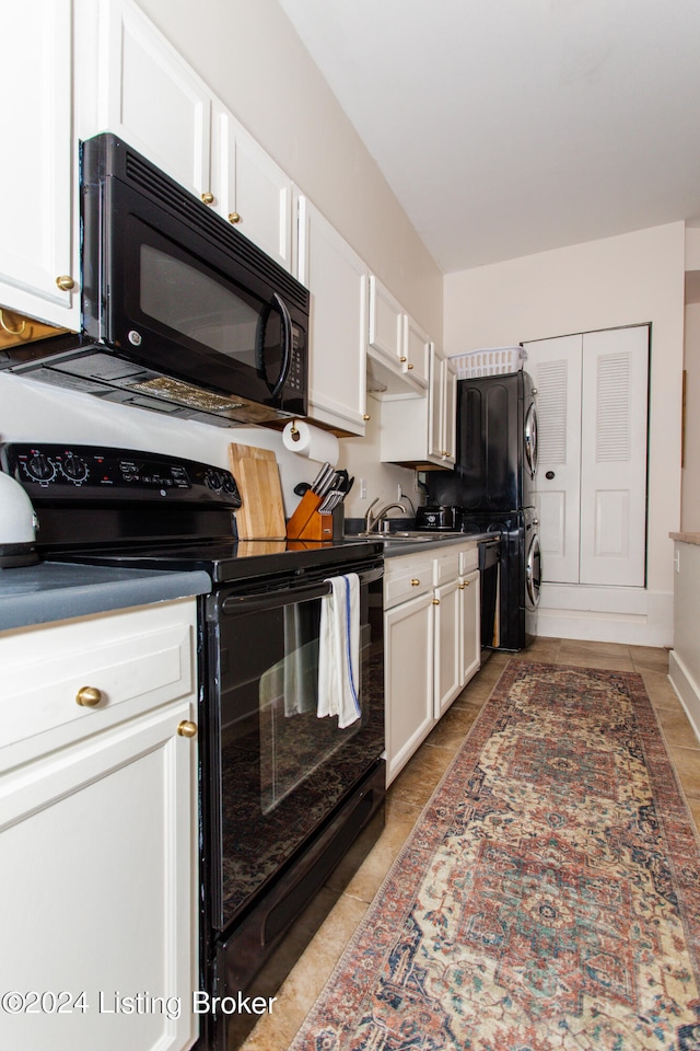 kitchen featuring light tile patterned floors, stacked washer and clothes dryer, white cabinets, and black appliances