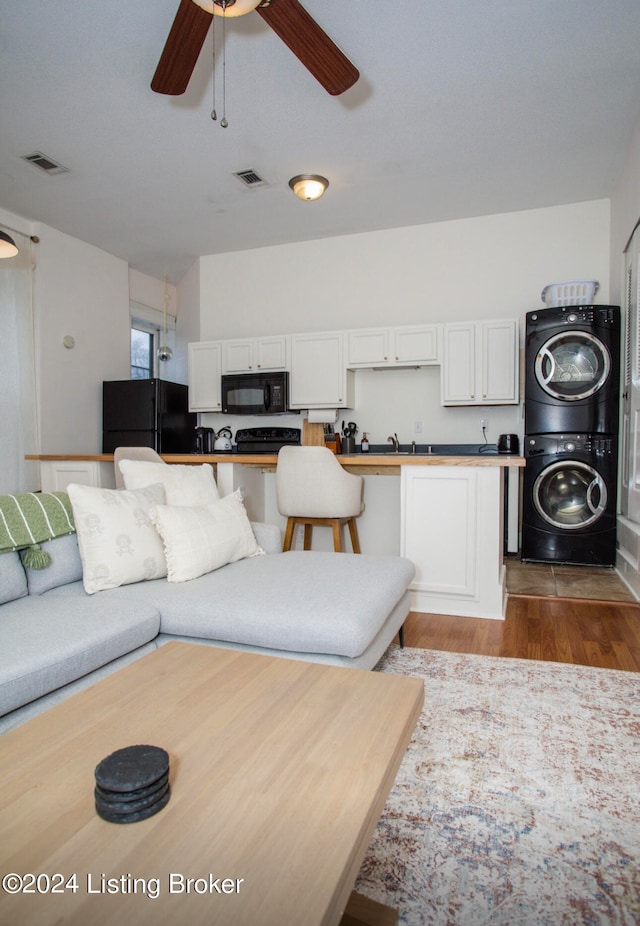 living room featuring ceiling fan, stacked washer and clothes dryer, and light hardwood / wood-style flooring