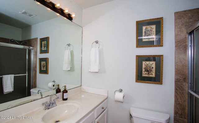 bathroom with an enclosed shower, vanity, and toilet