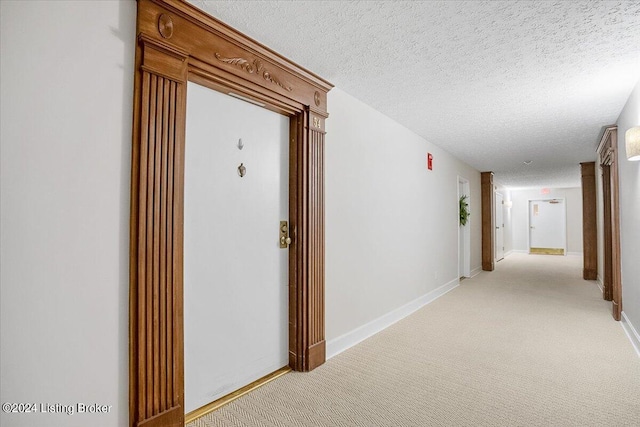 corridor with light carpet and a textured ceiling