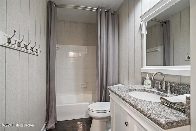 full bathroom with shower / bathtub combination with curtain, hardwood / wood-style flooring, vanity, and toilet