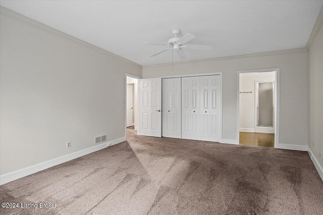 unfurnished bedroom featuring dark carpet, a closet, ensuite bath, ornamental molding, and ceiling fan